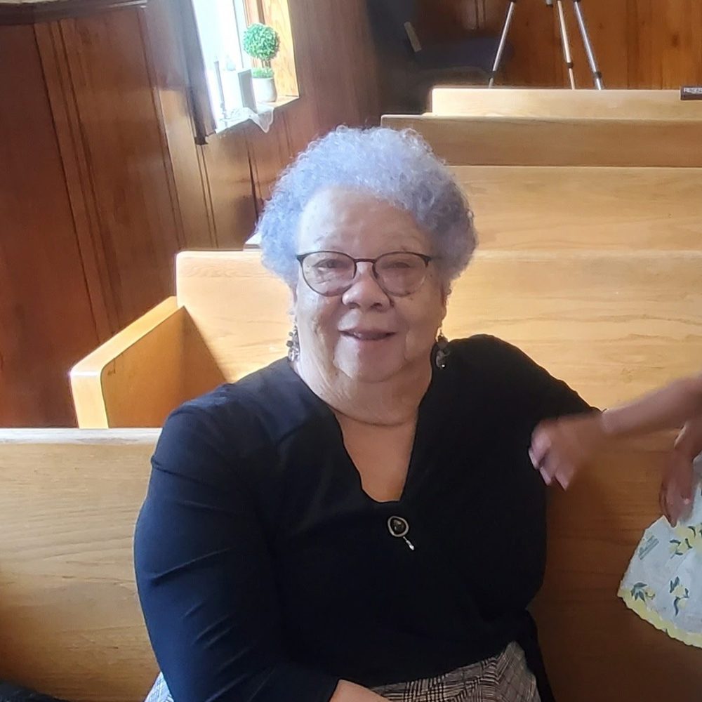 A smiling church mother seated in a pew at Star Bethel