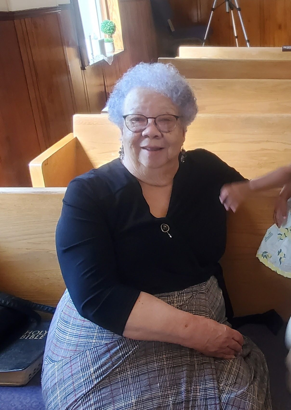 A smiling church mother seated in a pew at Star Bethel