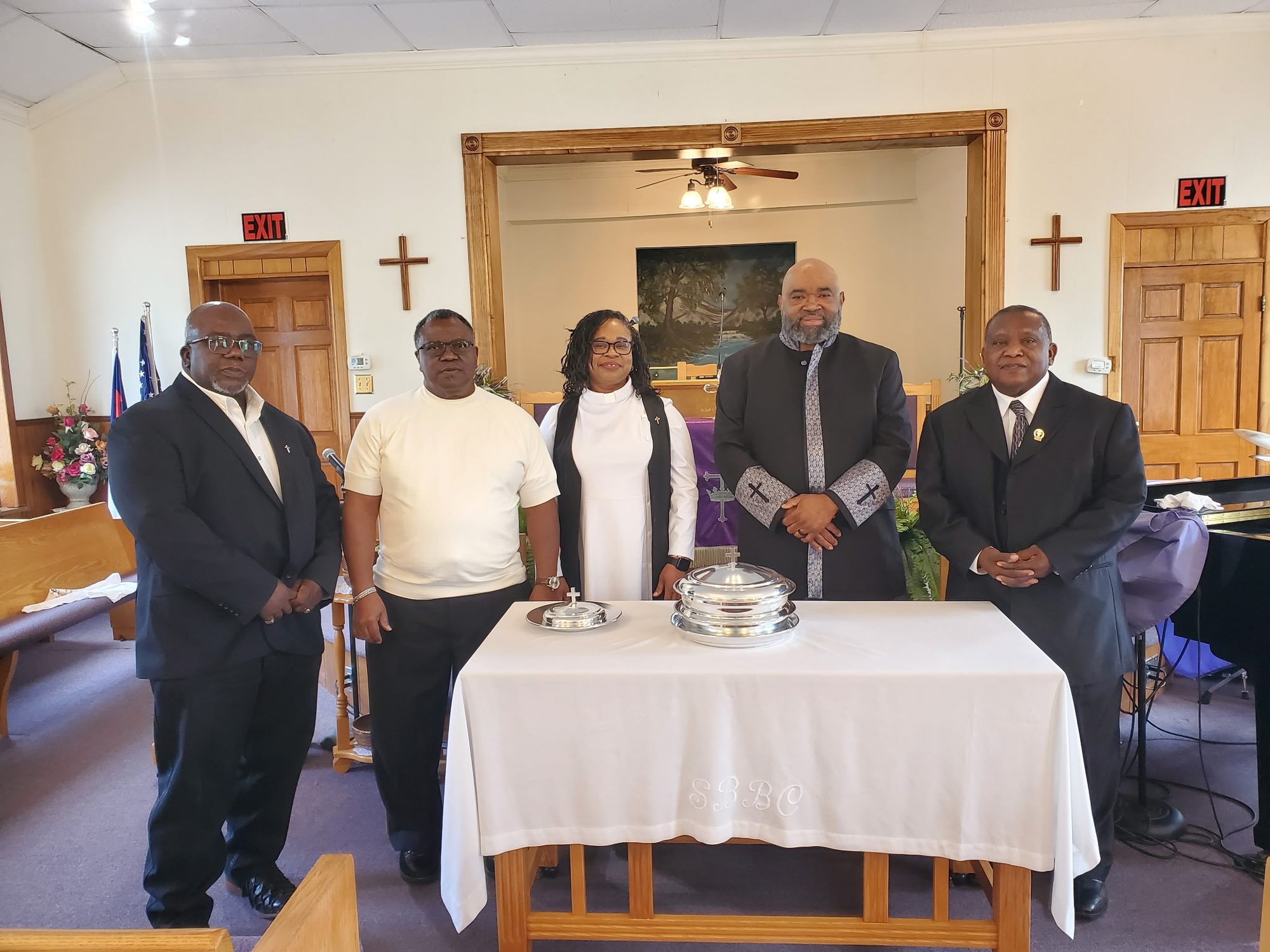 Pastor Parks and the deacons standing behind the Lord's Supper table at the front of the sanctuary