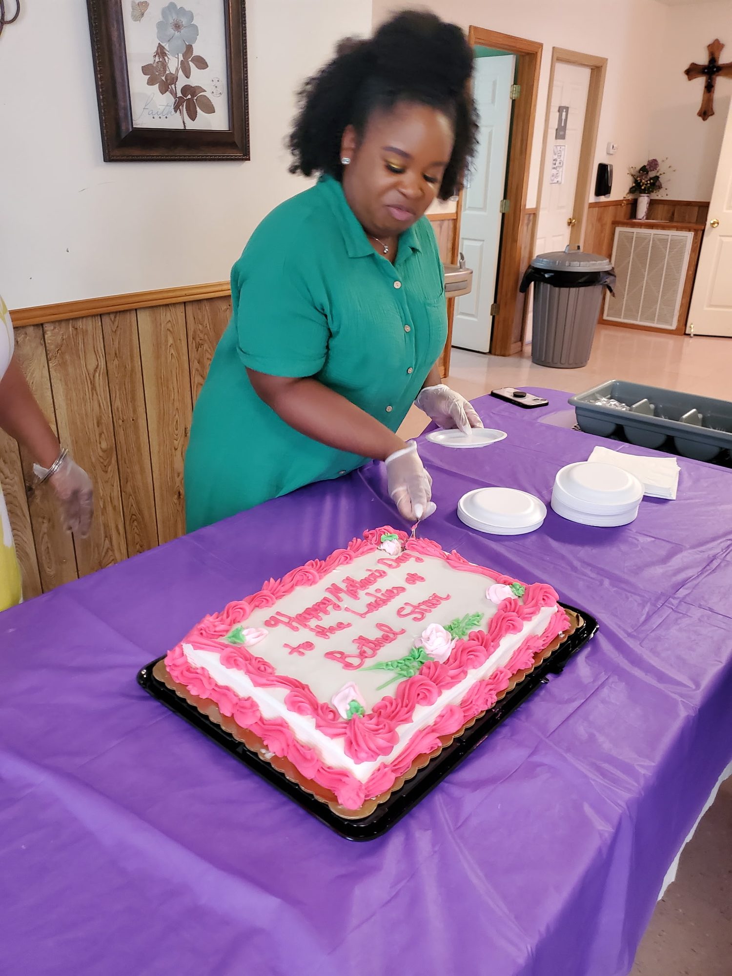 A member cutting a celebration cake at a fellowship meal in the fellowship hall