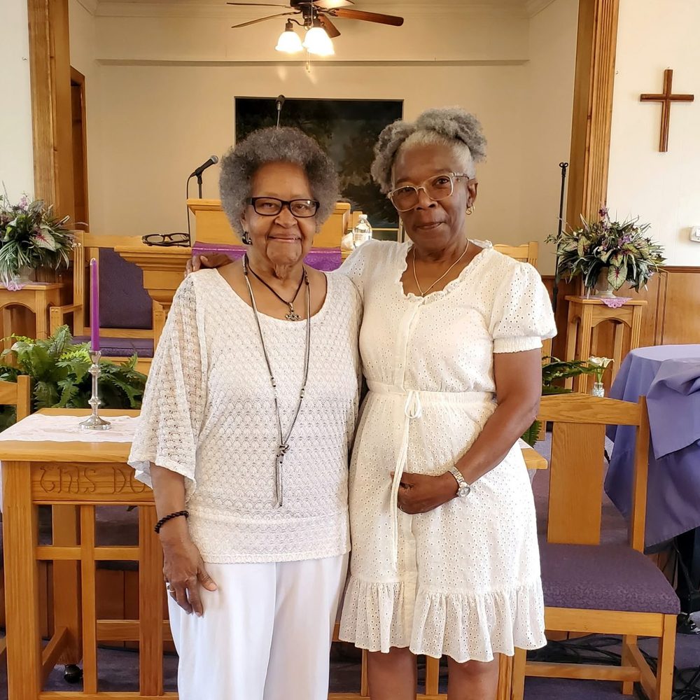 Two church mothers dressed in white in front of the pulpit
