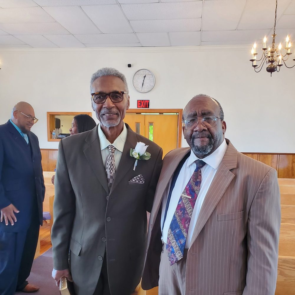 Two members of Star Bethel in suits smiling in the sanctuary